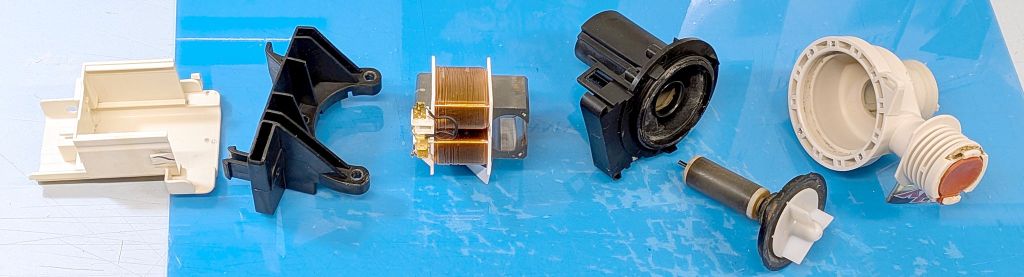 Exploded view of washing machine pump, including wiring guard, mounting bracket, AC electromagnet, rotor capsule, rotor with impeller, and pump housing.