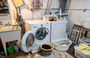 Laundry room in our house. Left to right: Tub sink, washer, dryer, breaker box, baskets of laundry