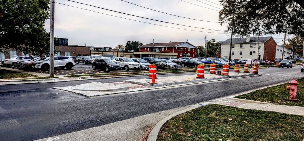 Street with half-completed new surfacing, and a completed pedestrian refuge island between the East and West lanes